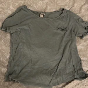 Grå t-shirt från H&M - Säljer en enkel grå t-shirt från H&M Basic-kollektionen. T-shirten har korta ärmar och en avslappnad passform, perfekt för en casual look. Tillverkad i mjukt material för extra komfort.