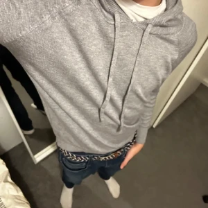 Grå hoodie - Säljer en stilren grå hoodie med dragsko i huvan. Tröjan har långa ärmar och ribbade muddar vid ärmslut och nederkant. Perfekt för en avslappnad look. Killen på bilden är 170 men tröjan sitter väldigt tajt. Skulle säga att den passar 160 - 165. Bilderna är lånad från killen jag köpte den av. Har inte använt den då den är för liten för mig. Hör av dig vid frågor. Priset kan diskuteras!