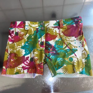 Färgglada shorts från Freddy - Säljer ett par färgglada shorts från Freddy med ett tropiskt mönster i grönt, rosa och blått. Shortsen har en knapp och dragkedja framtill samt praktiska fickor. Perfekta för en somrig look! Kan användas både till träning och en vanlig dag ute. Köptes för 600kr. 