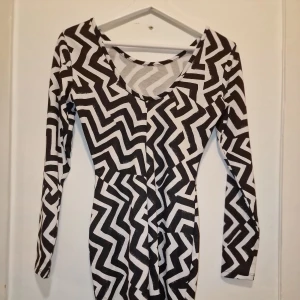 Svartvit mönstrad klänning från H&M - Snygg svartvit klänning med ett coolt, geometriskt mönster. Passar bra till både vardag och speciella tillfällen. Garderobsrensning så kika gärna på övriga auktioner.