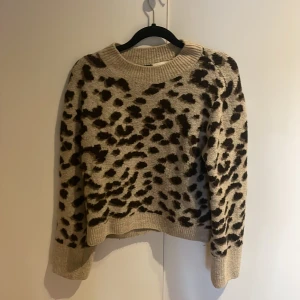 Beige leopardmönstrad stickad tröja - Säljer en snygg beige stickad tröja med leopardmönster. Tröjan har långa ärmar och en rund halsringning. Perfekt för att ge din outfit en trendig touch 🐆