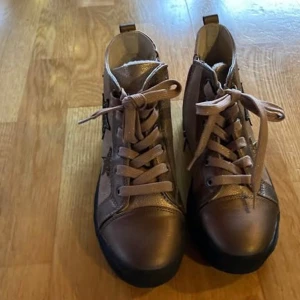 Bruna fodrade sneakers med stjärndetaljer - Snygga varmfodrade bruna sneakers med snörning och coola stjärndetaljer på sidan. Skorna har en bekväm passform och en robust sula som ger bra stöd. 
