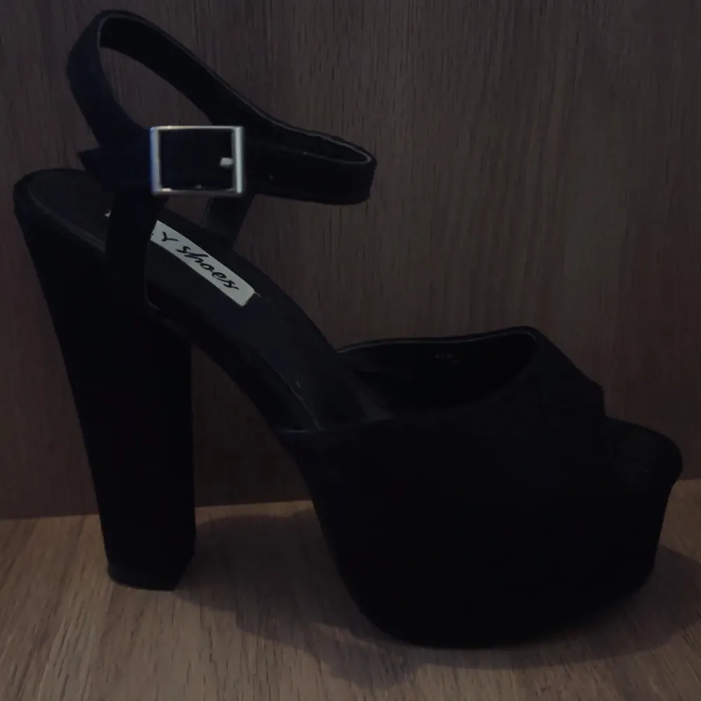 Snygga svarta klackar med hög klack och justerbar rem runt ankeln. Perfekta för att ge lite extra höjd och stil till din outfit. Klacken är stabil och ger bra stöd. Aldrig andvända. Storlek 36 med 13cm klack.. Kengät.