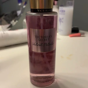 Victoria's Secret Velvet Petals Fragrance Mist - En doftspray från Victoria's Secret med namnet Velvet Petals. Flaskan är rosa och rymmer 250 ml. Doften beskrivs med noter av frodiga blommor och mandelglasyr, vilket ger en mjuk och romantisk känsla. Cirka 40-50% kvar