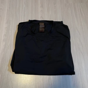 Svart tränings T-Shirt från NewBody - Snygg svart kortärmad t-shirt i syntetmaterial. Perfekt för träning eller vardagsbruk. Enkel och stilren design som passar till det mesta.