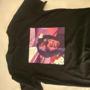 Svart t-shirt med Hello Kitty-tryck - Cool svart t-shirt med ett unikt Hello Kitty-tryck på framsidan. Perfekt för dig som gillar en mix av popkultur och humor. T-shirten har korta ärmar och en normal passform. Ett måste för alla Hello Kitty-fans!