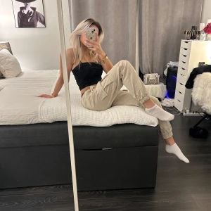 Beige cargobyxor med snörning - Säljer ett par snygga beige cargobyxor med praktiska fickor och snörning i midjan. Perfekta för en avslappnad stil och passar till många olika toppar. Byxorna har en loose passform och är tillverkade i ett bekvämt material.