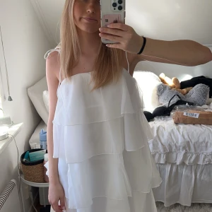 Vit klänning med volanger - Säljer en superfin vit klänning med flera lager volanger. Den har smala axelband och en luftig passform som ger en romantisk look. Perfekt för sommarens alla tillfällen! 🌸 Tänkte ha den på studenten men hittade en annan. Helt oanvänd!!💕