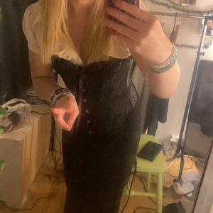 Svart korsett - Snygg svart korsett med snörning framtill. Perfekt för att ge en edgy touch till din outfit. Passar bra över en skjorta eller blus för en stilren look.