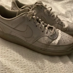 Vita Nike sneakers - Säljer ett par använda klassiska vita Nike sneakers med snörning. Storlek 46. Skorna har en stilren design med perforerade detaljer på tån för extra ventilation. Perfekta för en avslappnad stil. Pris kan diskuteras. Bra skick.