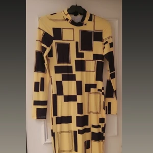 Gul och svart klänning från Shein - Säljer en cool gul klänning från Shein med svart geometriskt mönster. Klänningen har långa ärmar och en hög hals, perfekt för en unik look. Den är i storlek L och passar perfekt för dig som vill sticka ut.