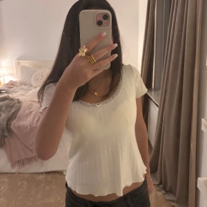 Vit topp från brandy Melville - Säljer en söt vit ribbad topp från Brandy Melville. Toppen har korta ärmar och en vacker spetskant runt den rundade halsringningen. Den är dekorerad med en liten rosett framtill. 💞💞