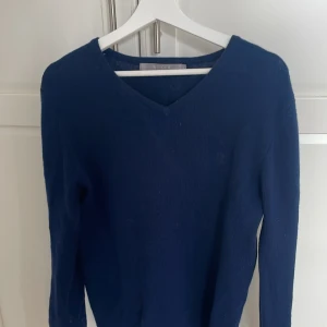 Mörkblå tröja från Tiger of Sweden - Säljer en stilren mörkblå tröja från Tiger of Sweden. Tröjan har en v-ringad hals och är tillverkad i ett mjukt material. Perfekt för en elegant och avslappnad look. Använd 2 gånger
