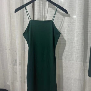 Grön axelbands klänning - Snygg grön klänning med smala axelband. Perfekt för en stilren look. Klänningen har en enkel design som gör den lätt att matcha med olika accessoarer.