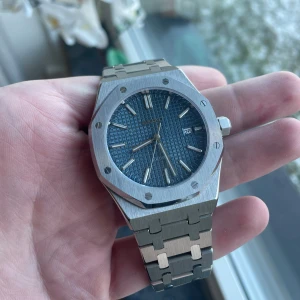Seiko ”AP” mod - Elegant Seiko AP Modiferad klocka med en distinkt blå urtavla och datumvisning. Boetten har en åttakantig form och armbandet är i borstat silverfärgat stål. Perfekt för den som söker en stilren och tidlös design.