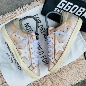 Golden Goose sneakers med stjärndetalj - Snygga Golden Goose sneakers i en unik design med stjärndetalj på sidan. Skorna har en sliten look med vita snören och en beige ton. Perfekta för en avslappnad stil med en touch av lyx.