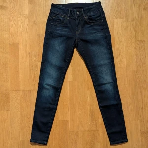 Mörkblå jeans från G-Star RAW - Snygga mörkblå skinny jeans från G-Star RAW med klassisk femficksdesign och kontrastsömmar. Modell  Lynn Mid Skinny, strl W 30, L 30. Innerbenslängd 74 cm. Liten i storleken. Mycket bra skick. Köpta på Zalando, nypris ca 1000 kr. 