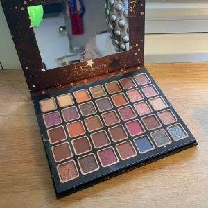 Bellápierre Ultimate Nude Eyeshadow Palette - Säljer en Bellápierre Ultimate Nude ögonskuggspalett med 35 olika färger. Paletten innehåller både matta och skimrande nyanser i jordnära toner, perfekt för att skapa både naturliga och dramatiska looks. Kompakt design med inbyggd spegel.