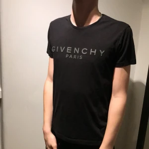 Svart t-shirt från Givenchy - Snygg svart t-shirt från Givenchy med tryck i silver på bröstet. Den har en klassisk rund hals och korta ärmar, perfekt för en stilren look.