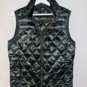 Uniqlo väst - Snygg quiltad väst med camouflage-mönster och dragkedja. Perfekt för en cool och avslappnad stil. Storlek S