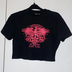 Svart croppad t-shirt med rosa tryck - Snygg svart croppad t-shirt med ett rosa tryck. ✨