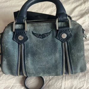 Blå mockaväska från Zadig & Voltaire - Sparsamt använd Zadigväska i modellen Sunny Nano Suede i en cool blå färg. Väskan är i mocka och är i mycket fint skick då den förvarats i sin dustbag majoriteten av tiden sedan jag köpte den i butik. Dustbag och prislapp medföljer.
