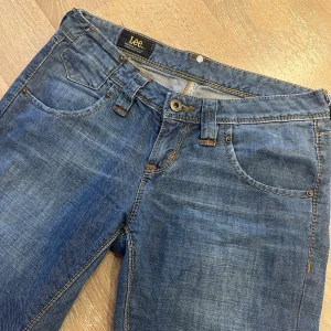 Blå jeans från Lee - Snygga blå jeans från Lee med klassisk femficksdesign och orange sömmar💕De har en knappgylf och bälteshällor, perfekt för en avslappnad stil😊 Passformen är rak och de är tillverkade i slitstarkt denim. Inga slitningar alls🩷