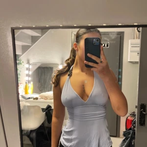 Syrenlila Guess halterneck topp - Snygg guess syrenlila halterneck topp med djup urringning och knytband i nacken. Toppen har en dekorativ svart detalj vid axelbanden och en tight passform som framhäver figuren.