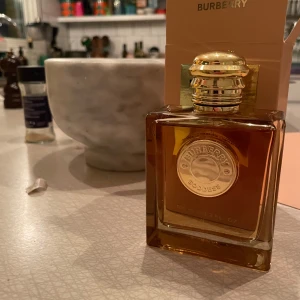 Burberry Goddess Intense Eau de Parfum - Elegant parfym från Burberry i en lyxig glasflaska med guldlock. Doften heter Goddess intense och kommer i en stilren förpackning med guldiga detaljer. Perfekt för den som vill ha en sofistikerad och tidlös doft.
