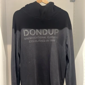 Svart hoodie från Dondup - Snygg svart hoodie från Dondup med texten 'Unconventional Clothing Established in 1999' på framsidan. Perfekt för en avslappnad stil med en bekväm passform och huva. Storlek M men  passar L också