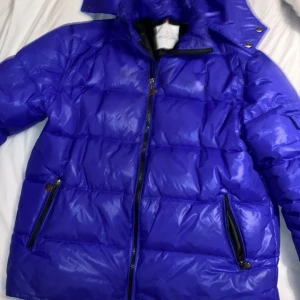 Lila pufferjacka från Moncler - Säljer en snygg blå pufferjacka från Moncler. Jackan har en quiltad design med dragkedja och huva, perfekt för kyliga dagar. Den är i mycket bra skick och har en broderad Moncler-logga på bröstet. Passar perfekt för både höst och vinter!    Jackan är S/M. Priset kan ändras. Skriv om du har några frågor!  SKRIV T MIG INNAN DU KÖPER!!