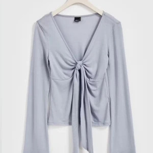 Ljusblå topp med knytning - Super snygg ljusblå långärmad från gina. den är använd ett fåtal gånger och kommer inte till så mycket användning vilket är anledningen till varför jag säljer denna. den är köpt för 300 kr