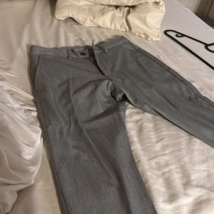 Grå kostymbyxor från Zara - Säljer ett par stiliga grå kostymbyxor från Zara i mycket bra skick. De har en elegant passform med dragkedja och knapp framtill. Perfekta för både kontoret och festliga tillfällen.