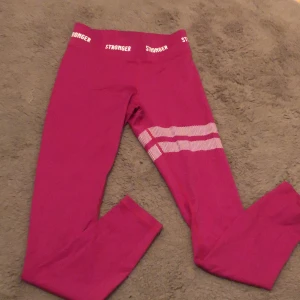 Rosa träningsset från Stronger - Säljer ett snyggt rosa träningsset från Stronger i storlek small. Setet består av en sport-bh och matchande tights, båda med elastisk midja och logotypdetaljer. Materialet är 75% återvunnen polyester och 25% elastan, perfekt för träning. Använd få gånger och i mycket bra skick!