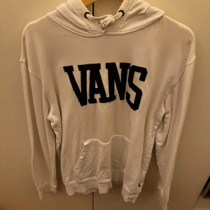 Vit hoodie från Vans - Säljer en snygg vit hoodie från Vans i storlek medium. Den har en stor svart Vans-logga på framsidan och texten 'Off The Wall' på insidan av kragen. Perfekt för en avslappnad stil och passar till alla tillfällen. Den är i bra skick och superbekväm att ha på sig. 🖤