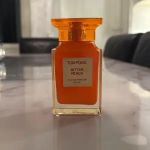 Säljer en lyxig Tom Ford Bitter Peach Eau de Parfum, 100 ml. Flaskan är i en snygg orange färg med en elegant design. Perfekt för den som älskar en fruktig och sensuell doft. Flaskan är nästan full och i perfekt skick. Passa på att köpa denna exklusiva parfym!