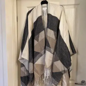 Säljer en superfin poncho från Vila i geometriskt mönster. Den har en mix av beige, grå och vit som gör den perfekt för höst och vår. Materialet känns mjukt och mysigt, och den har fransar längst ner för en extra touch. Perfekt att slänga över axlarna för en stilren look!