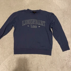 Blå sweatshirt från Lee - Säljer en snygg blå sweatshirt från Lee i storlek M. Tröjan har texten 'LEGENDARY' tryckt på framsidan och är i ett mjukt och bekvämt material. Perfekt för en avslappnad stil eller som ett lager under jackan. Passar både höst och vår!