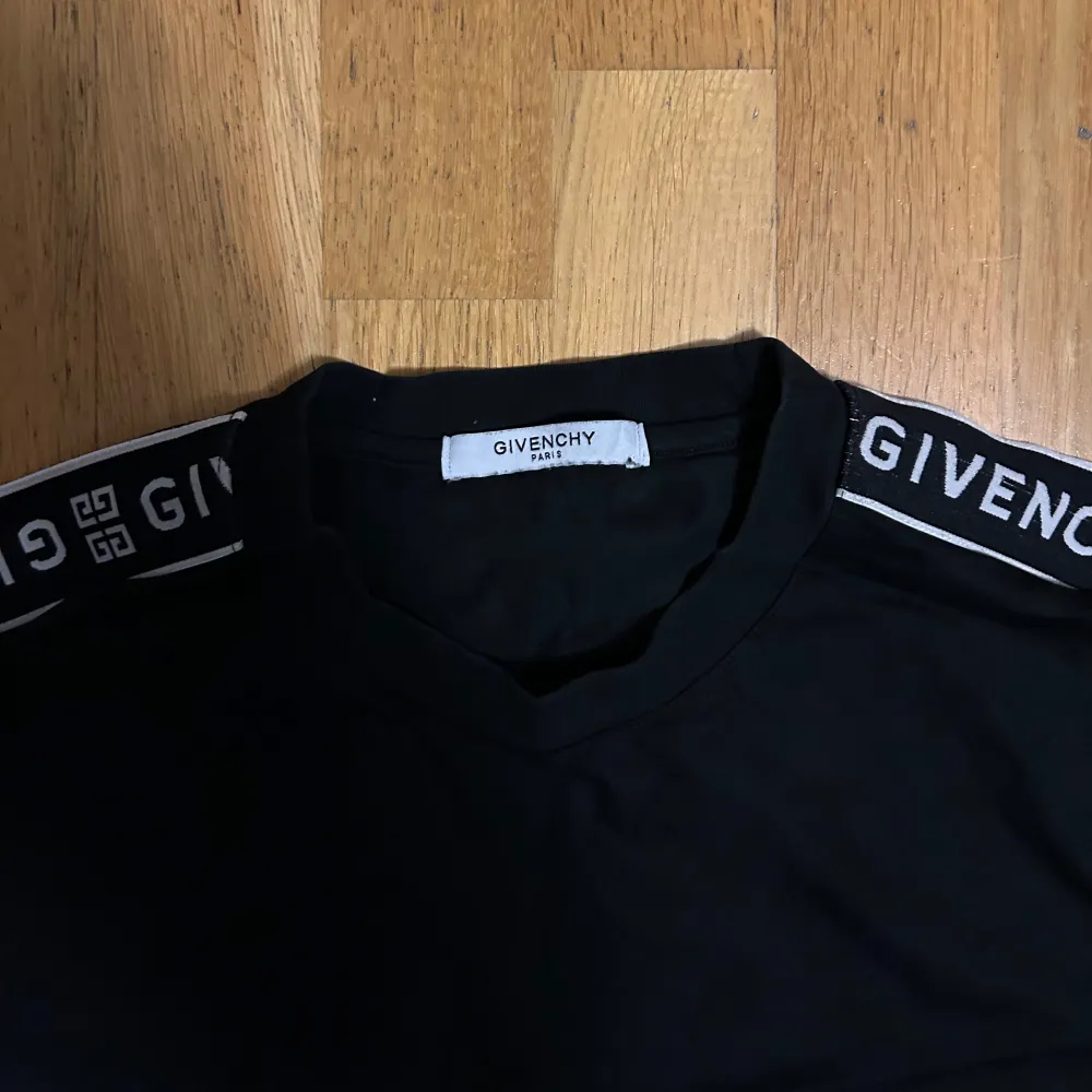 Säljer en snygg svart t-shirt från Givenchy i mycket bra skick. Den har korta ärmar med Givenchy-loggan tryckt längs axlarna. Perfekt för en stilren och modern look. Passar både till vardags och fest! Står storlek L men den är mer som S-M. T-shirts.