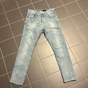 Säljer ett par ljusblå jeans från Tiger of Sweden i modellen Pistolero. De är i bra skick och har en klassisk femficksdesign med dragkedja och knapp. Perfekta för både vardag och fest! 🕺                            Nypris: 1600kr