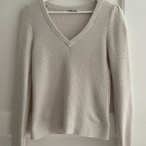 Beige stickad tröja med v-ringning - Säljer en supermysig beige/vit stickad tröja med v-ringning. Låna armar och ribbat material.