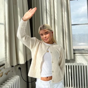 Beige stickad kofta - Mysig beige stickad kofta med knappar framtill. Perfekt för kyliga dagar och ger en avslappnad men stilren look. Passar bra till både vardag och festliga tillfällen.