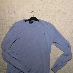 Blå tröja från Polo Ralph Lauren - Säljer en snygg blå tröja från Polo Ralph Lauren i bra skick. Den är långärmad och har en liten broderad logga på bröstet. Perfekt för både vardag och lite finare tillfällen. Vid smidig affär kan ja gå ner till 450