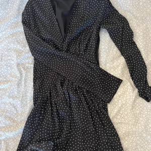 Svart prickig klänning från ADOORE - Aldrig använd. Säljer en elegant svart klänning från ADOORE i storlek 32. PASSAR ÄVEN 34! Den har ett stilrent prickigt mönster och långa ärmar. Perfekt för både vardag och festliga tillfällen. Klänningen har en smickrande passform och är i mycket bra skick. Nypris ca 1200