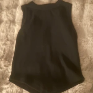 Svart ärmlös topp från Boohoo - Säljer en stilren svart ärmlös topp från Boohoo i storlek S. Perfekt för både vardag och festliga tillfällen. Toppen är i bra skick och har en enkel design som gör den lätt att matcha med olika outfits. Den är även formad som en triangel i änden som ger en snygg kroppsform 🖤