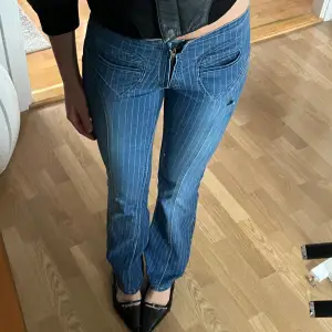 Säljer ett par snygga blå jeans med vita ränder. De är lågmidjade och har en bootcut-stil som ger en retro vibe. Perfekta för både vardag och fest! De har en dragkedja fram och är i bra skick. Jag är 173!!❤️❤️