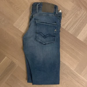 Blå jeans från Replay - Säljer ett par snygga blå jeans från Replay i storlek 29/32, knappt använda. De har en klassisk femficksdesign och en bekväm passform. Perfekta för både vardag och fest! 🕺