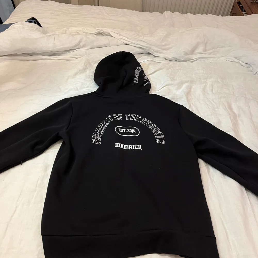 Säljer en svart hoodie från Hoodrich i storlek L. Den har en cool design med röd och vit text på framsidan och baksidan. Perfekt för en avslappnad stil och passar bra till höst och vinter. Hoodien är i mycket bra skick och är nästan aldrig använd samt har en skön passform.. Tröjor & Koftor.