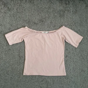 Ljusrosa offshoulder topp från NA-KD - Säljer en superfin ljusrosa offshoulder topp från NA-KD. Den är perfekt för sommardagar och har en tight passform som framhäver figuren. Toppen är i ett mjukt och bekvämt material, perfekt för både vardag och fest!
