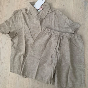Oanvänt beiget set från Monki, stl S - Jättesnyggt set med skjorta och shorts, från Monki i en beige härlig färg! Säljer pga för litet och hann inte returnera. Helt oanvänt! 